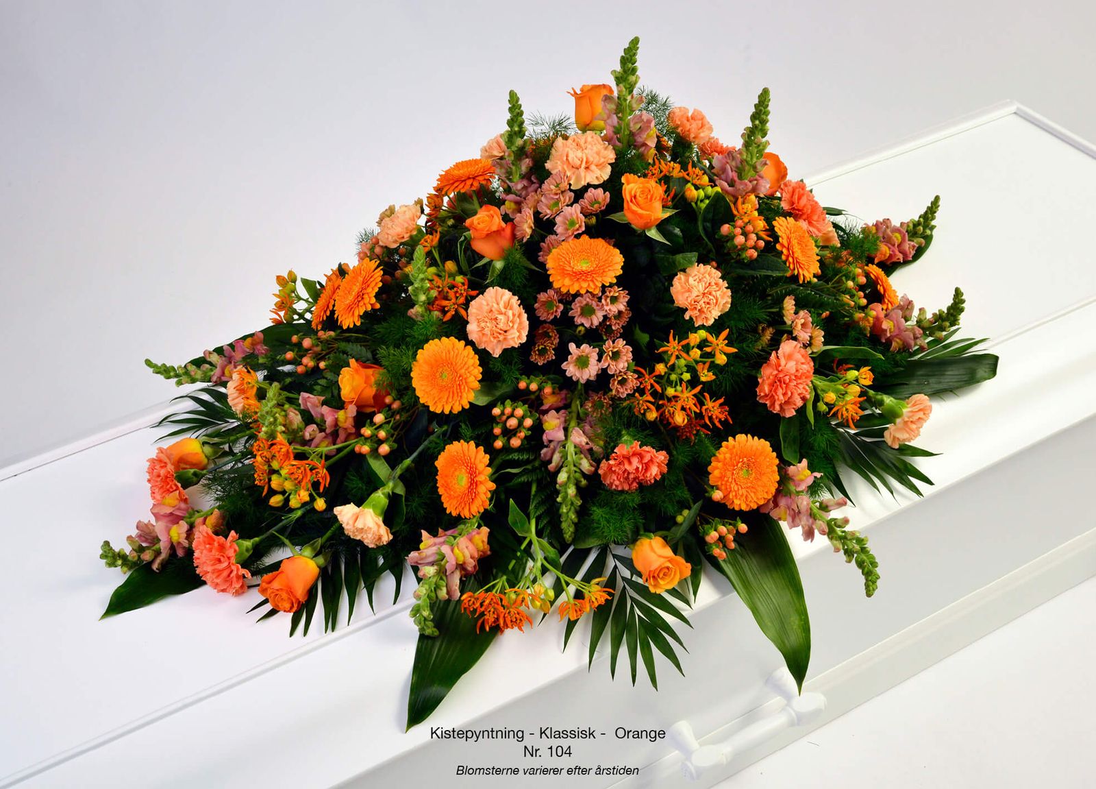 Floral photography styling showcases orange wreath with carnations, gerbera and roses in elegant arrangement