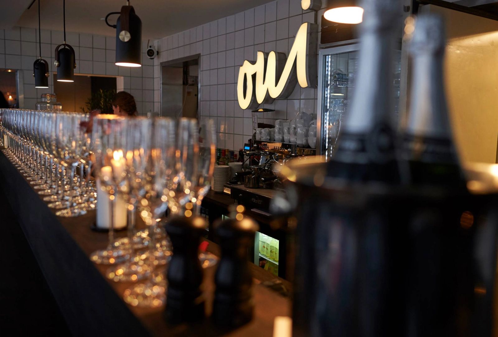 Interior design af elegant French bistro bar med belyst logo, glas på rad og moderne pendellamper