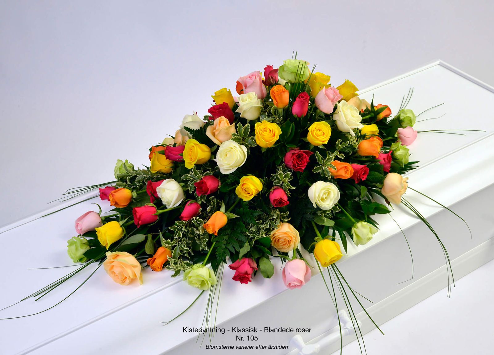 Funeral catalogue design: multicolored rose arrangement with red, yellow, white and orange blooms on white casket drape