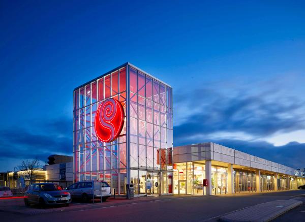 Brand identity og retail design — Rosengårdcentret shoppingcenter ved skumringstid med oplyst rød logo-tårn