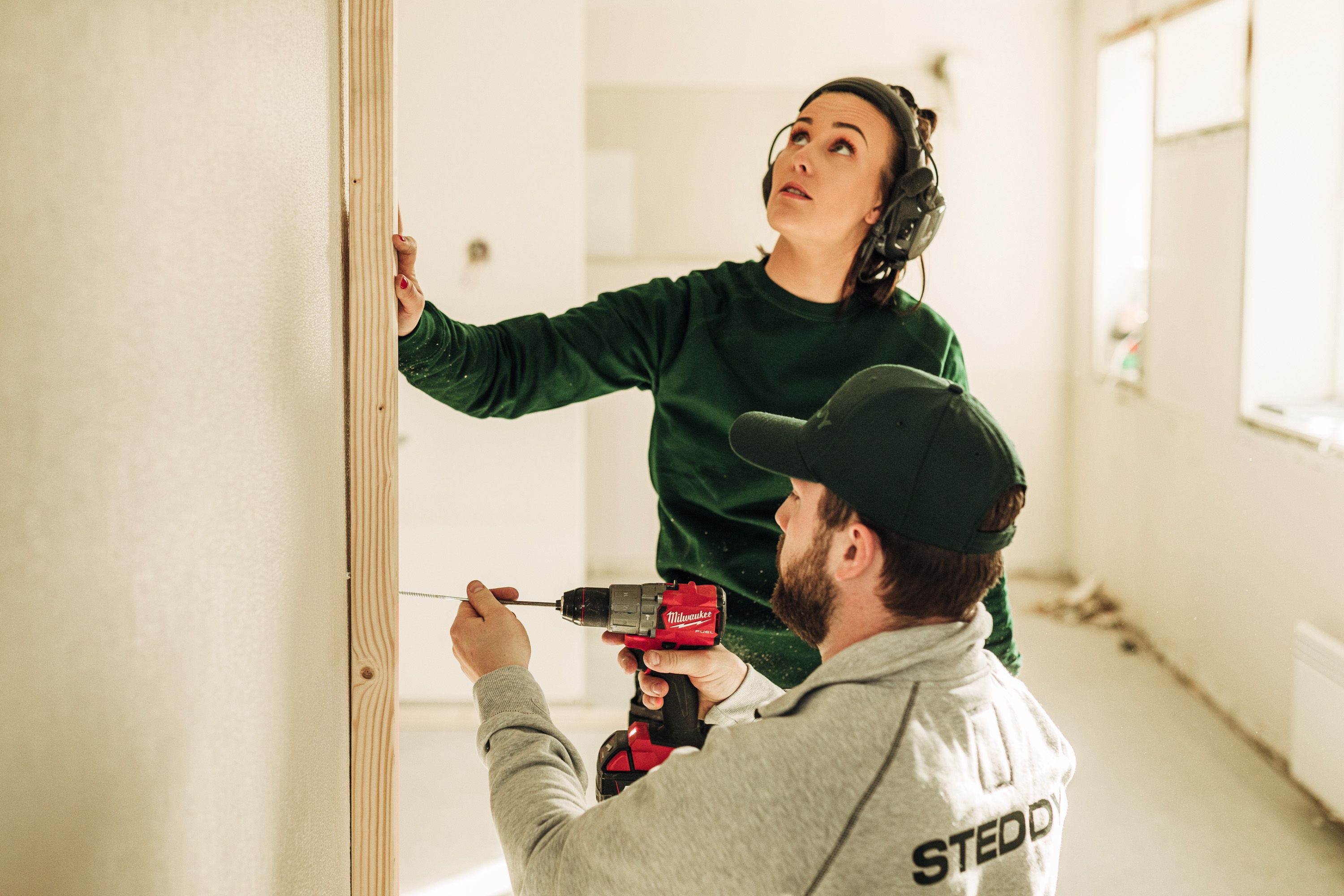 To Steddy håndverkere som pusser opp en vegg