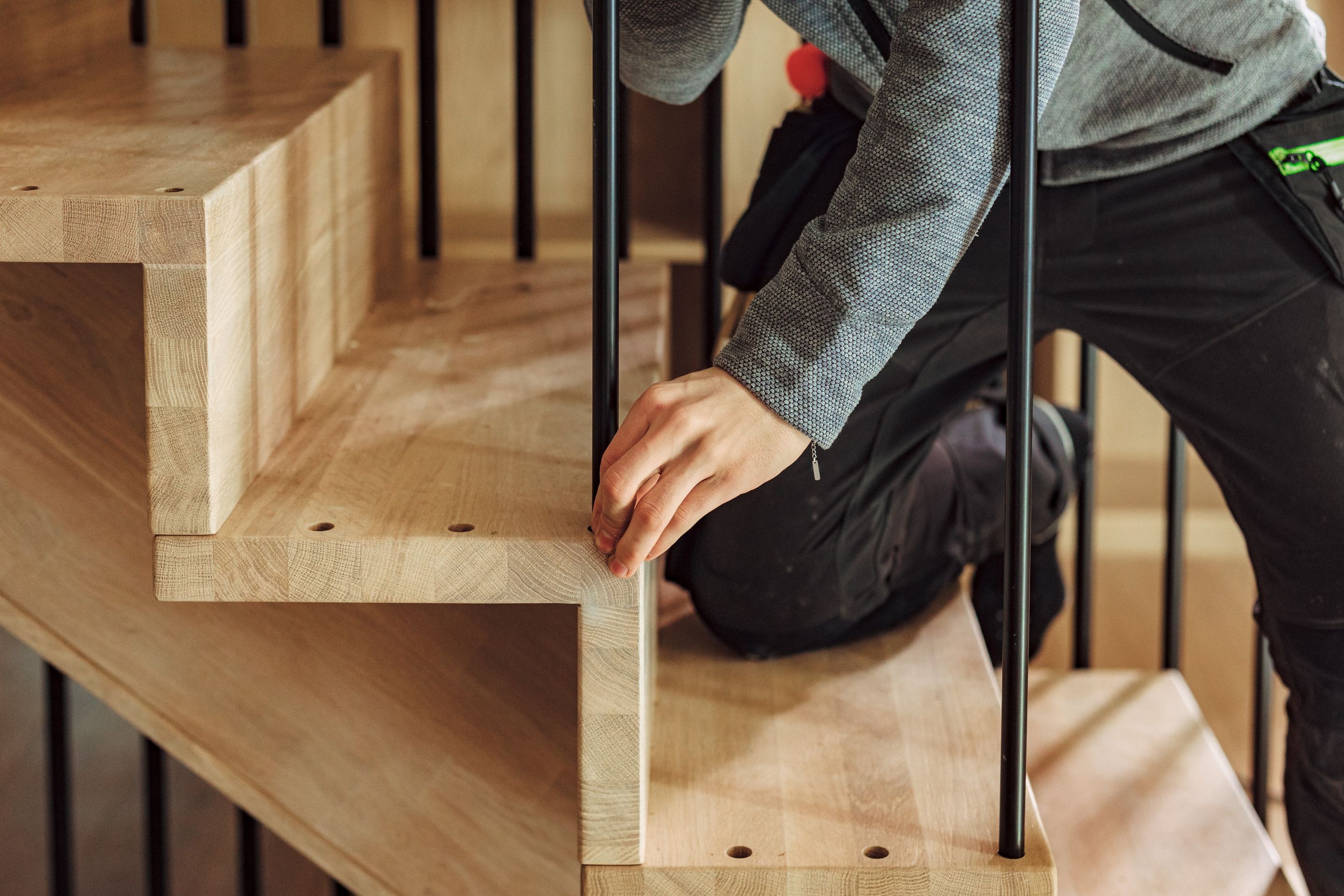 Nærbilde av en håndverker som monterer spiler på en trapp