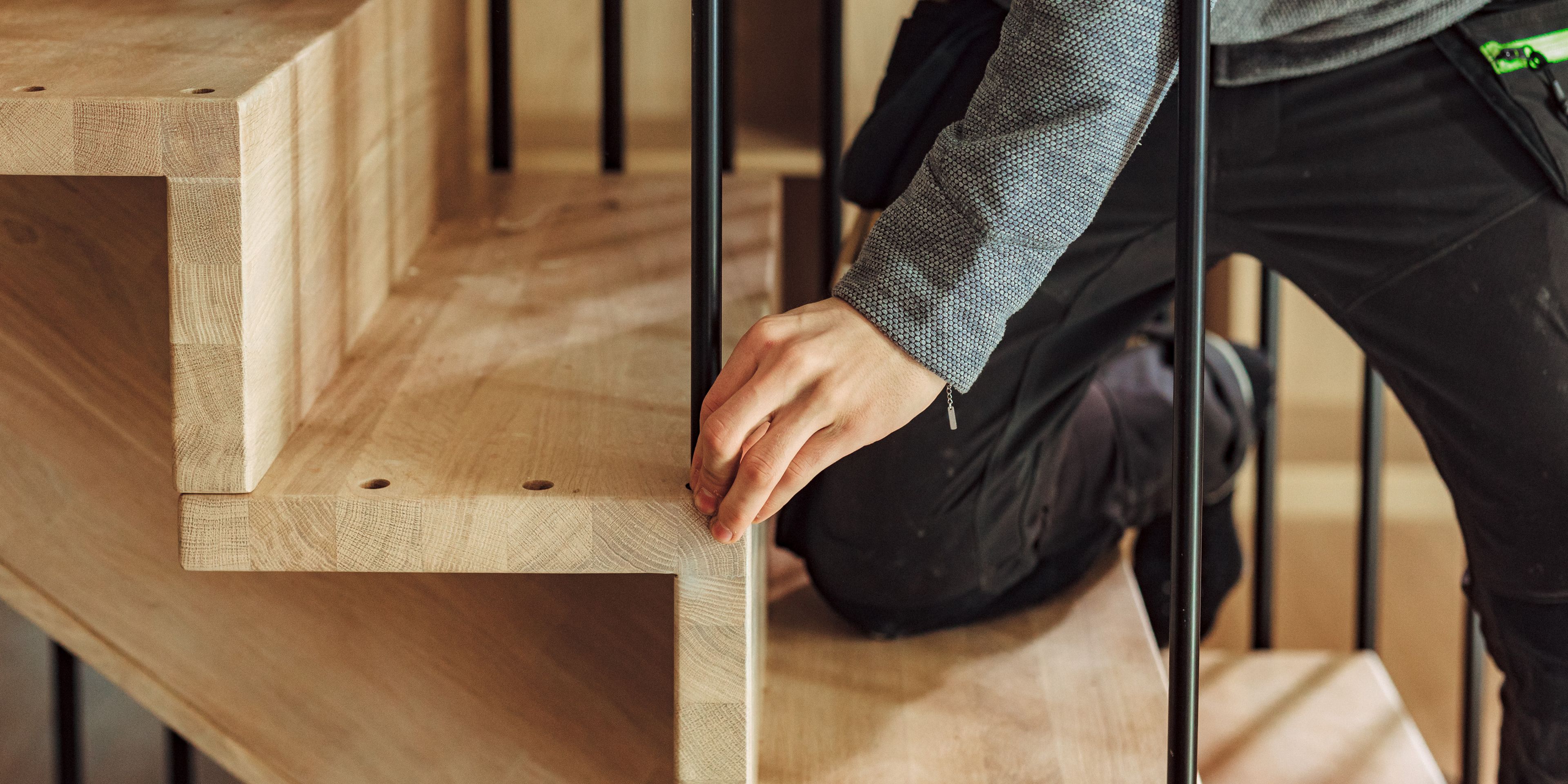 Nærbilde av en håndverker som monterer spiler på en trapp