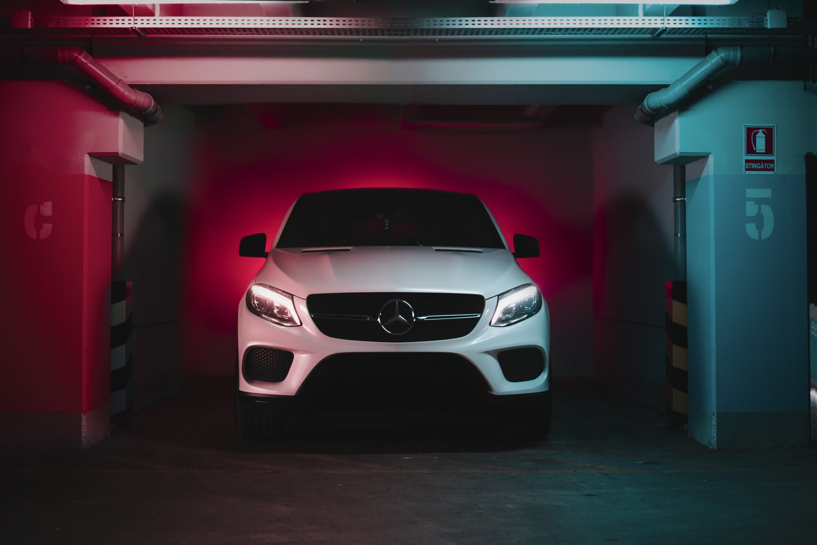 Silver coupe under red light in a garage