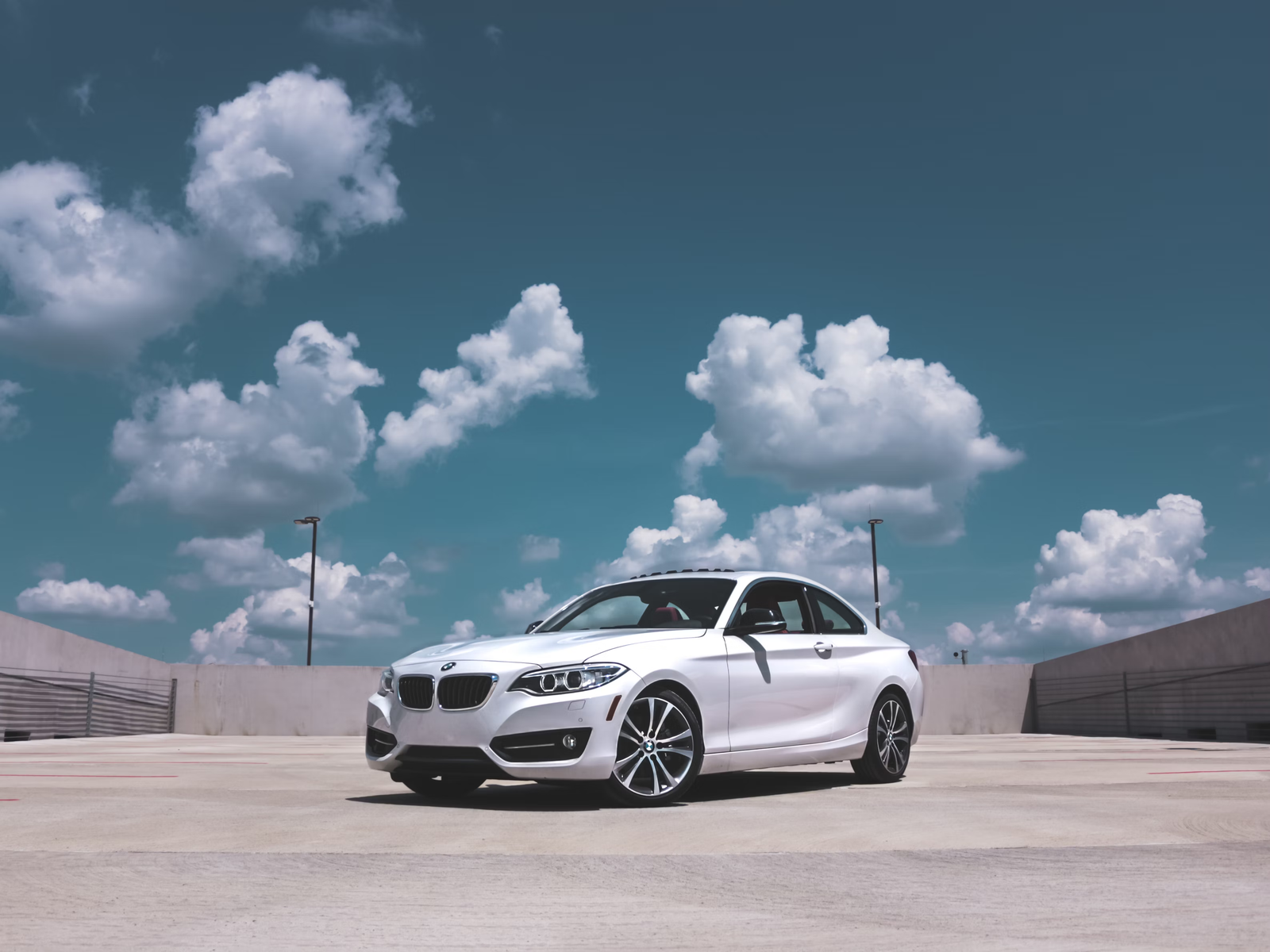 White coupe in a parking lot under a cloudy sky