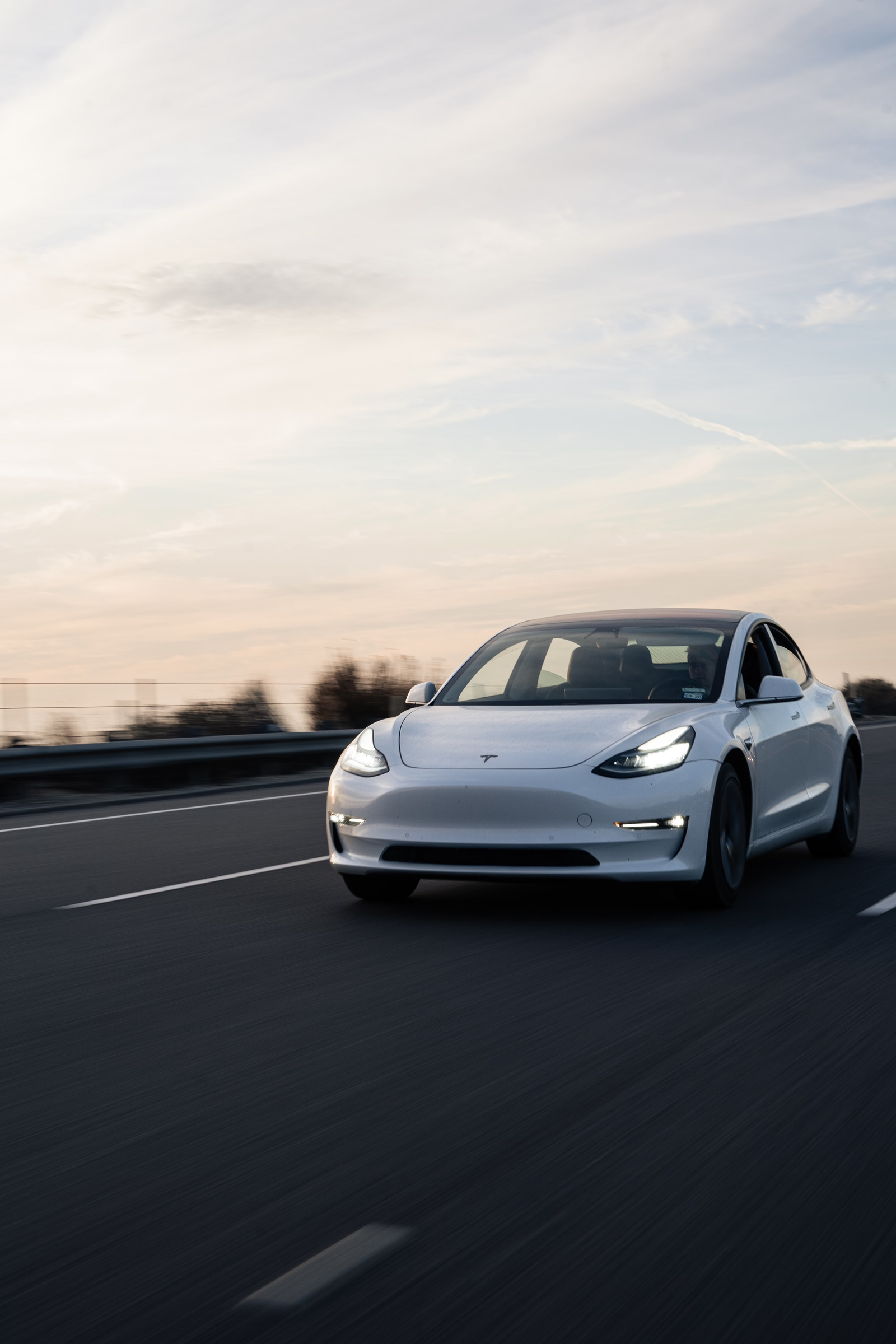White electric sedan driving on an open road