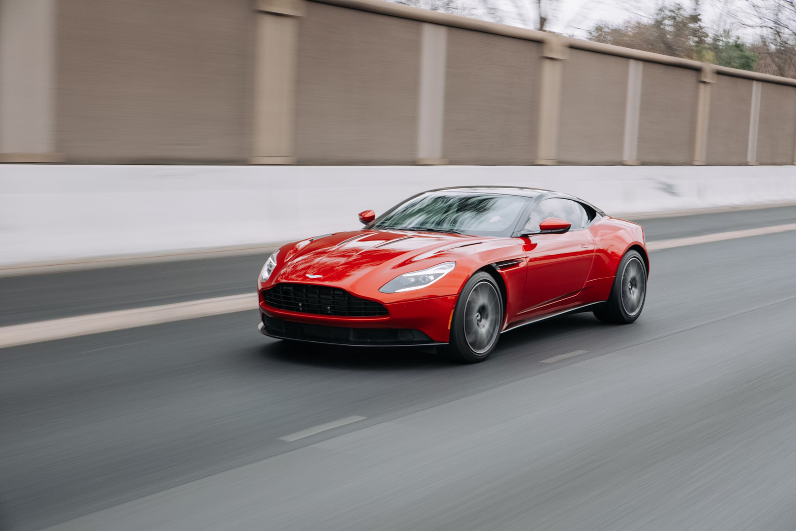Red grand tourer driving on a city road