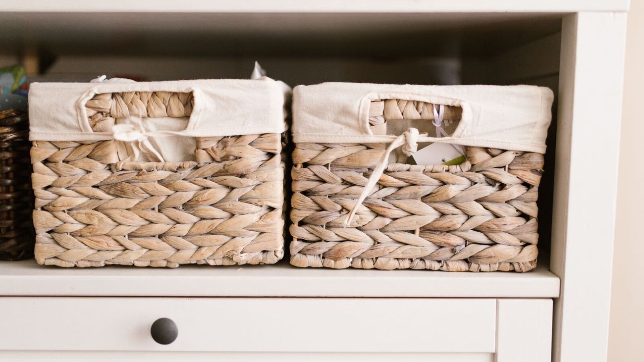 Two linen-lined woven baskets on a white storage shelf.