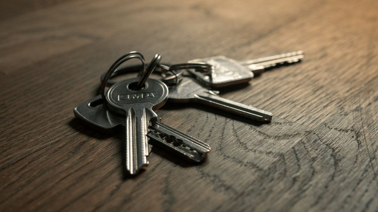 A ring of house keys lying on a dark oak table in soft side light.