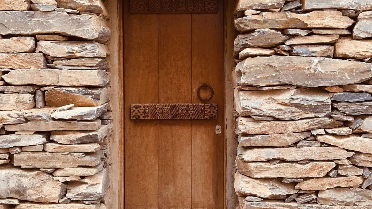 A weathered wooden door set into a dry-stacked stone wall.
