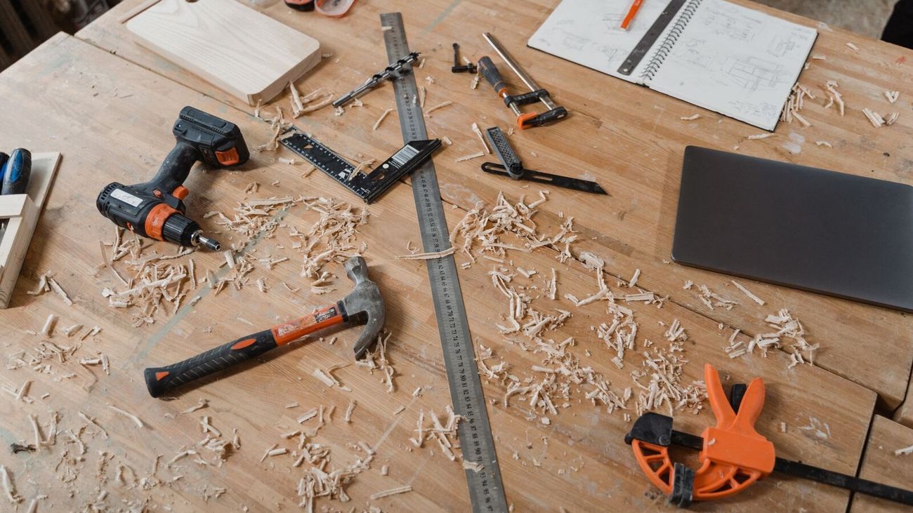 Hand tools, a ruler and wood shavings spread across a pale wooden workbench.