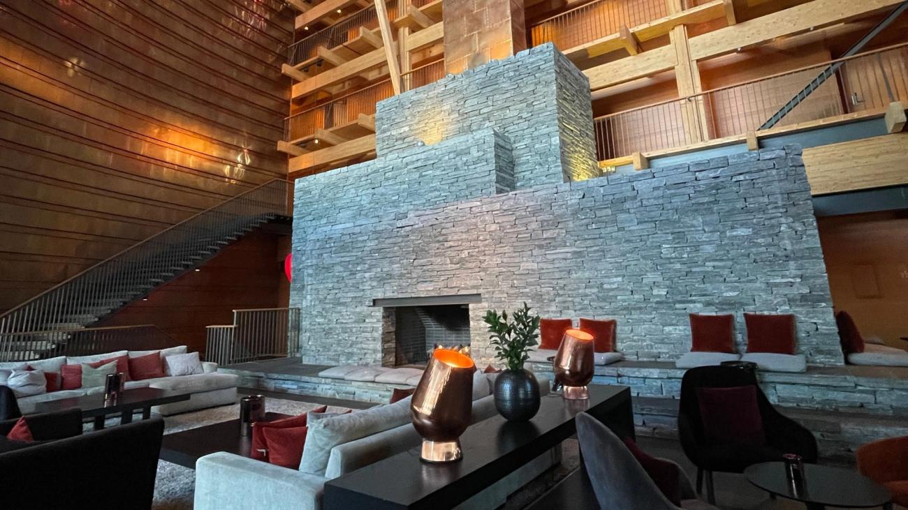 Hotel lounge with a stacked stone fireplace, timber balconies and amber table lamps