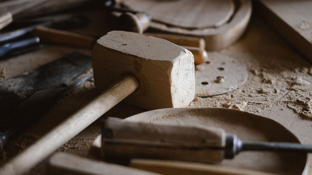 A wooden mallet and chisels resting among sawdust on a carpenter's bench.