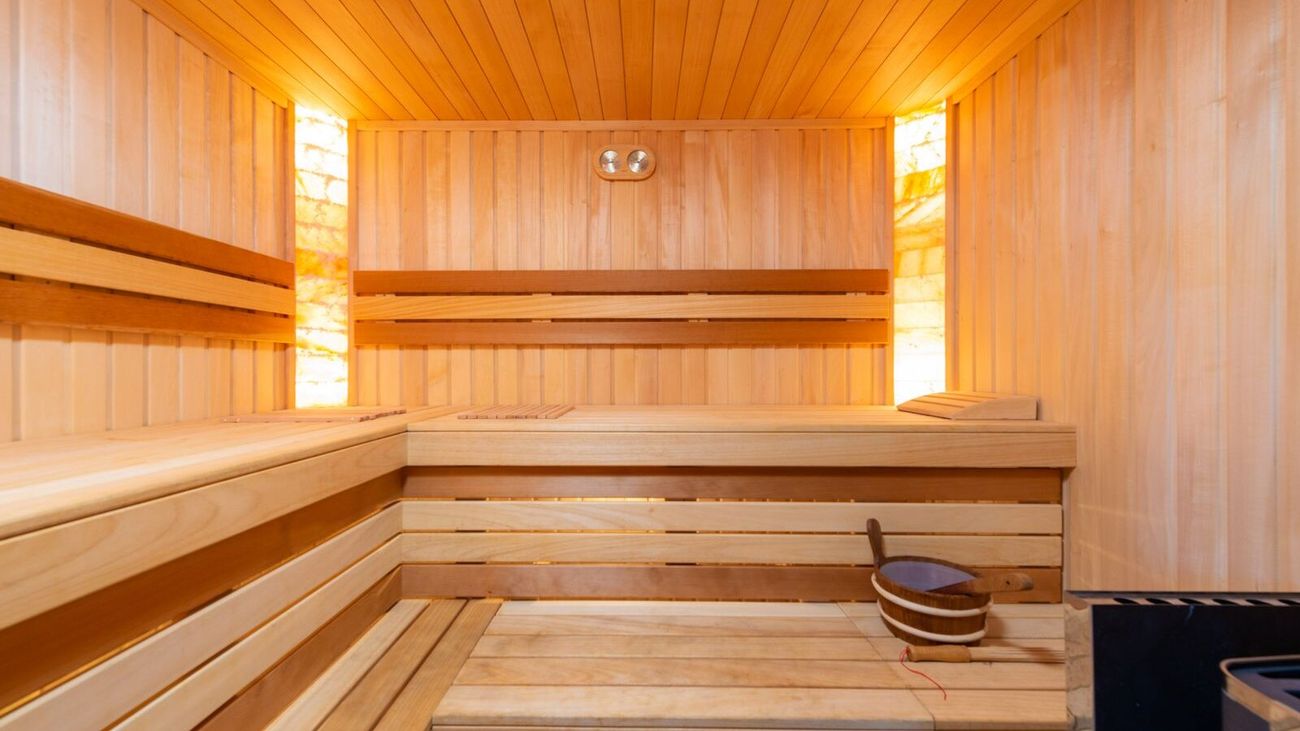 An empty wooden sauna lit by warm wall lamps.