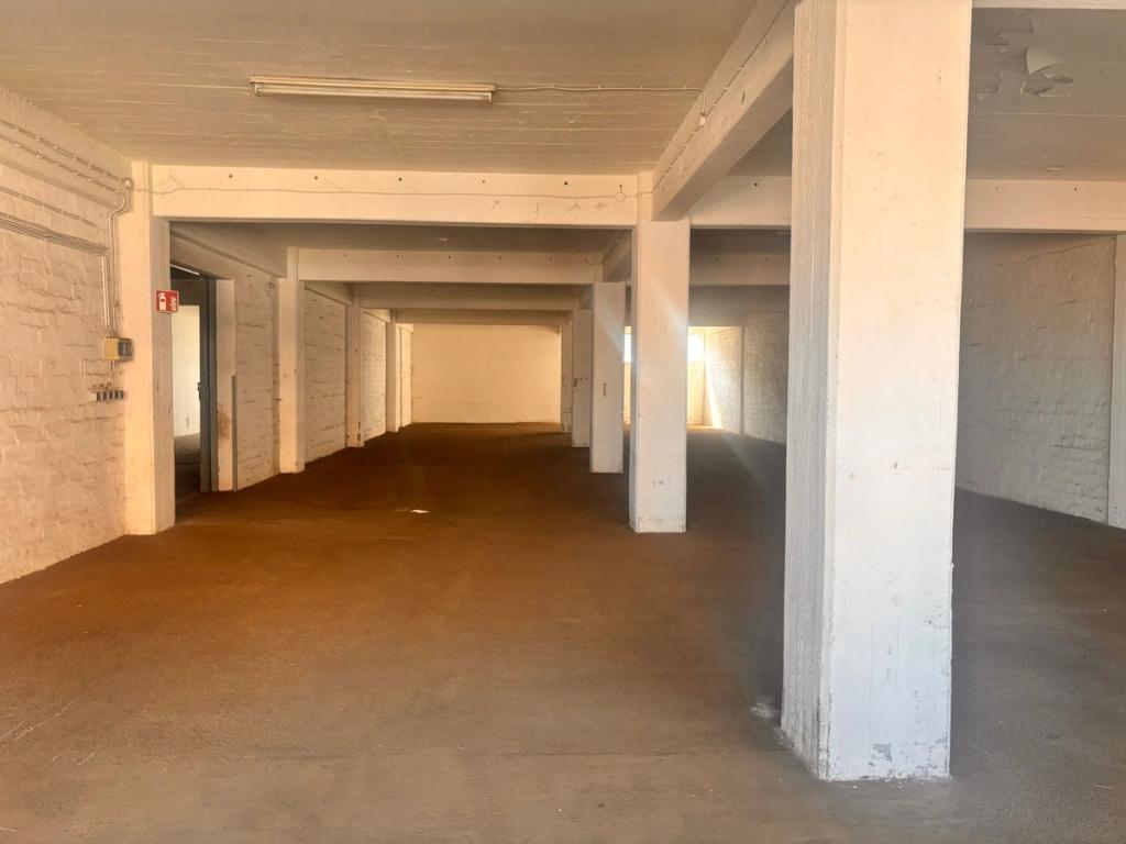 Empty workspace with white concrete walls and ceilings and dusty floor.
