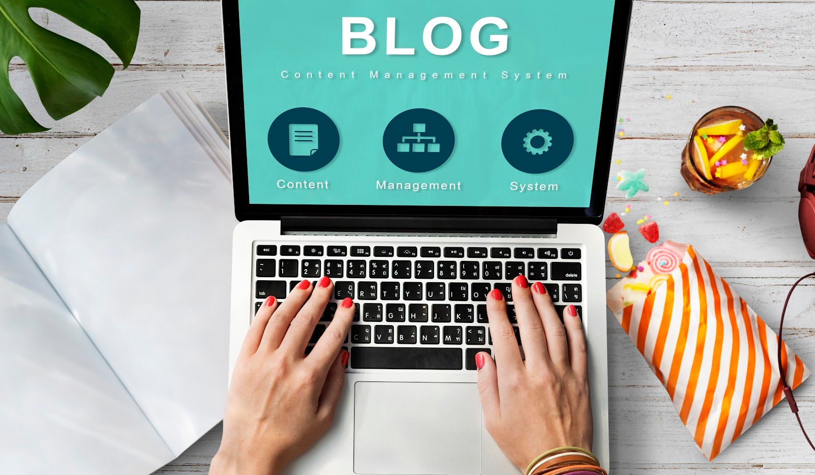 Hands type on a laptop screen displaying "BLOG" and icons.