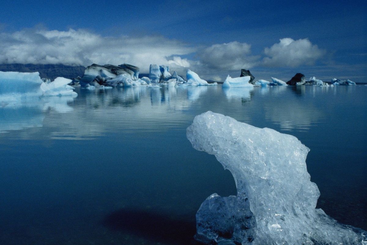 Iceberg azul translúcido emergiendo del agua en la laguna glaciar de Jökulsárlón