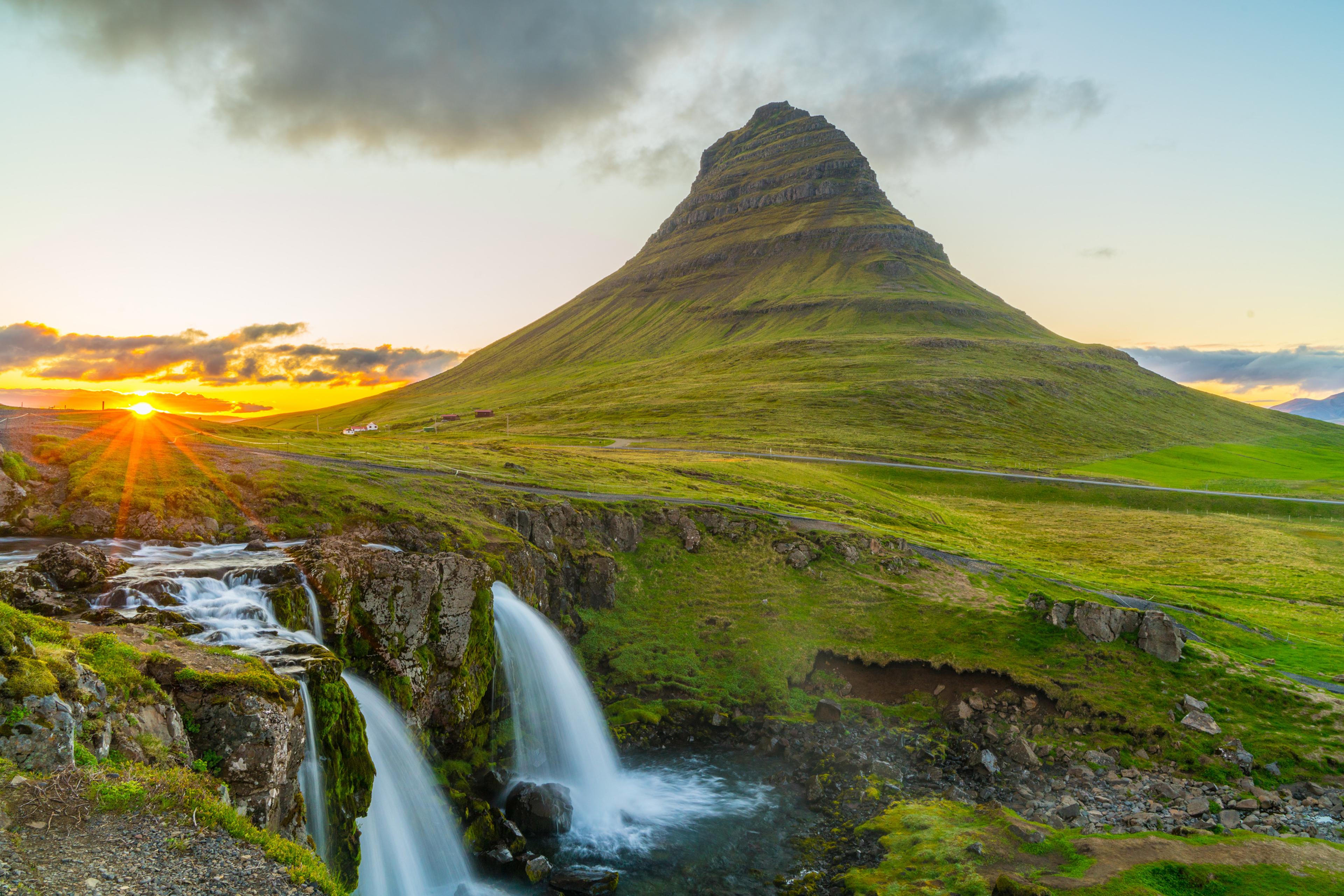 La montaña Kirkjufell con la cascada Kirkjufellsfoss en primer plano al atardecer, península de Snæfellsnes