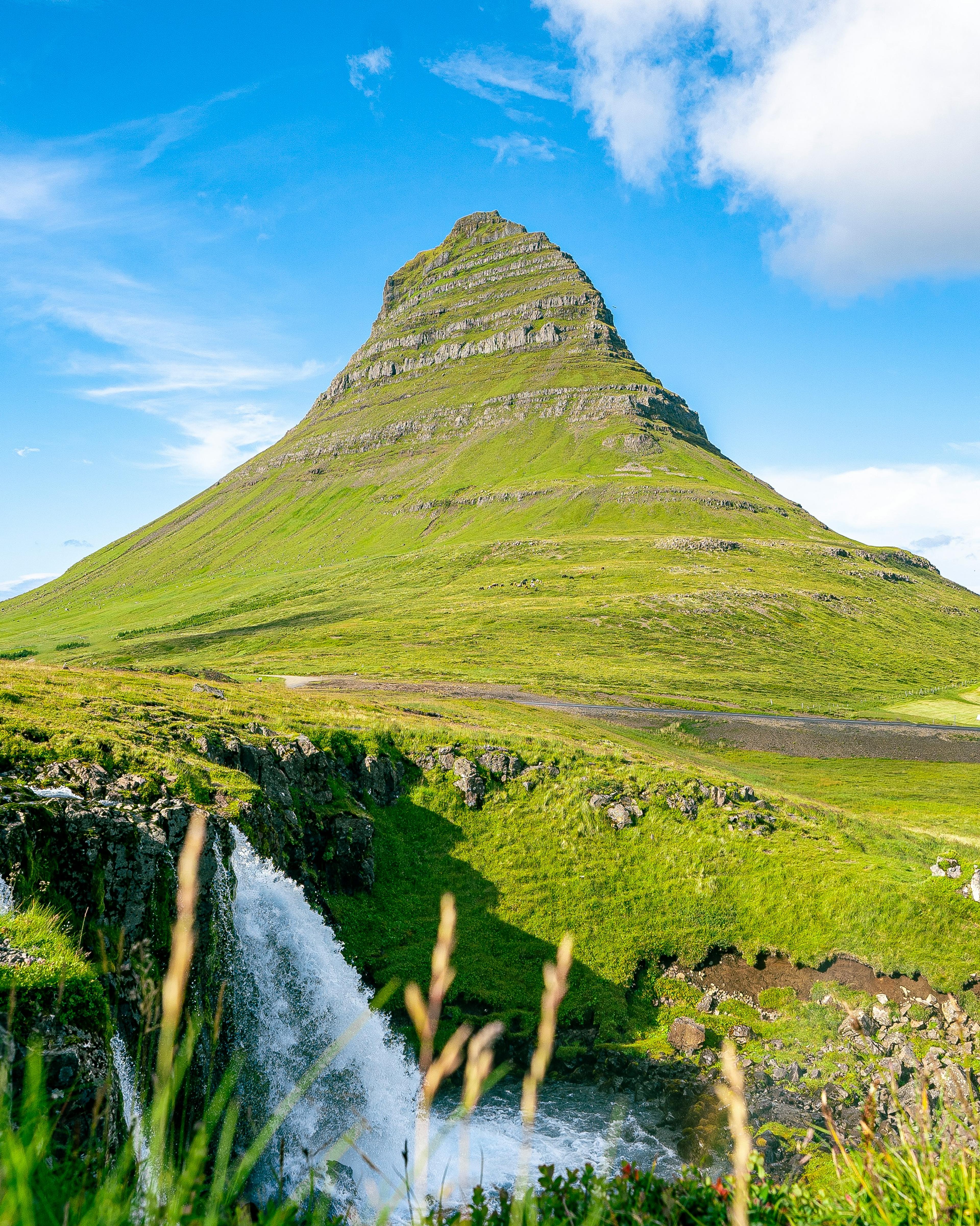La montaña Kirkjufell rodeada de hierba verde al atardecer, Islandia a finales de verano