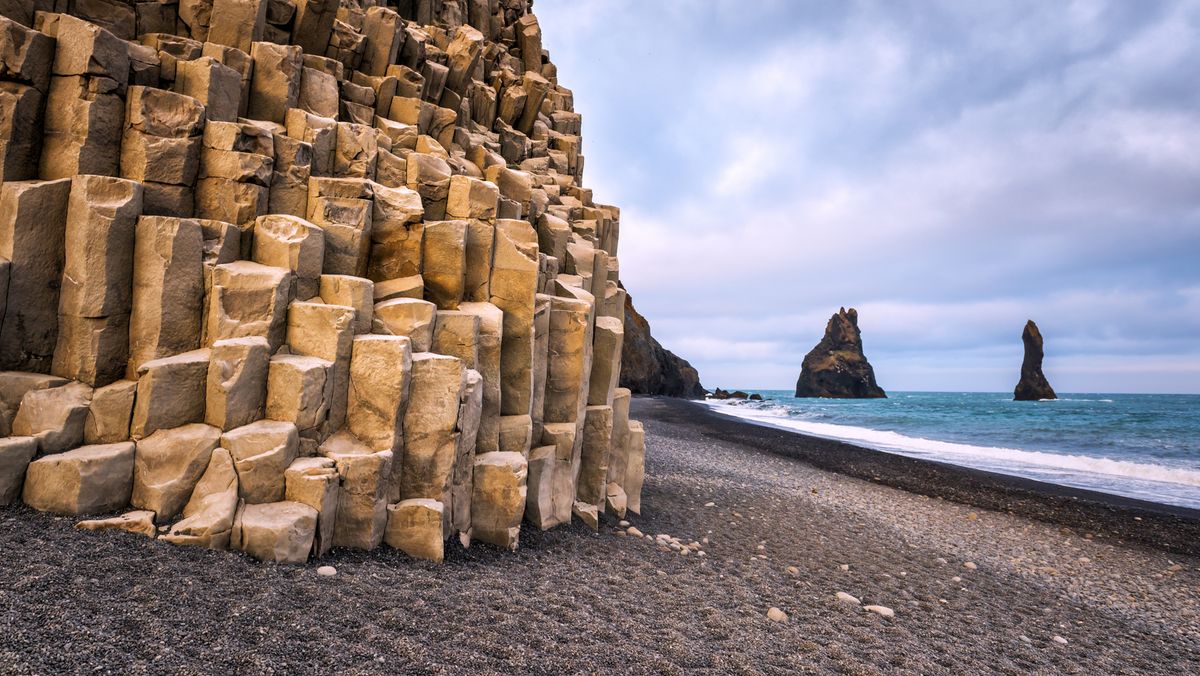 Columnas de basalto hexagonales en la playa negra de Reynisfjara, con los farallones de Reynisdrangar al fondo