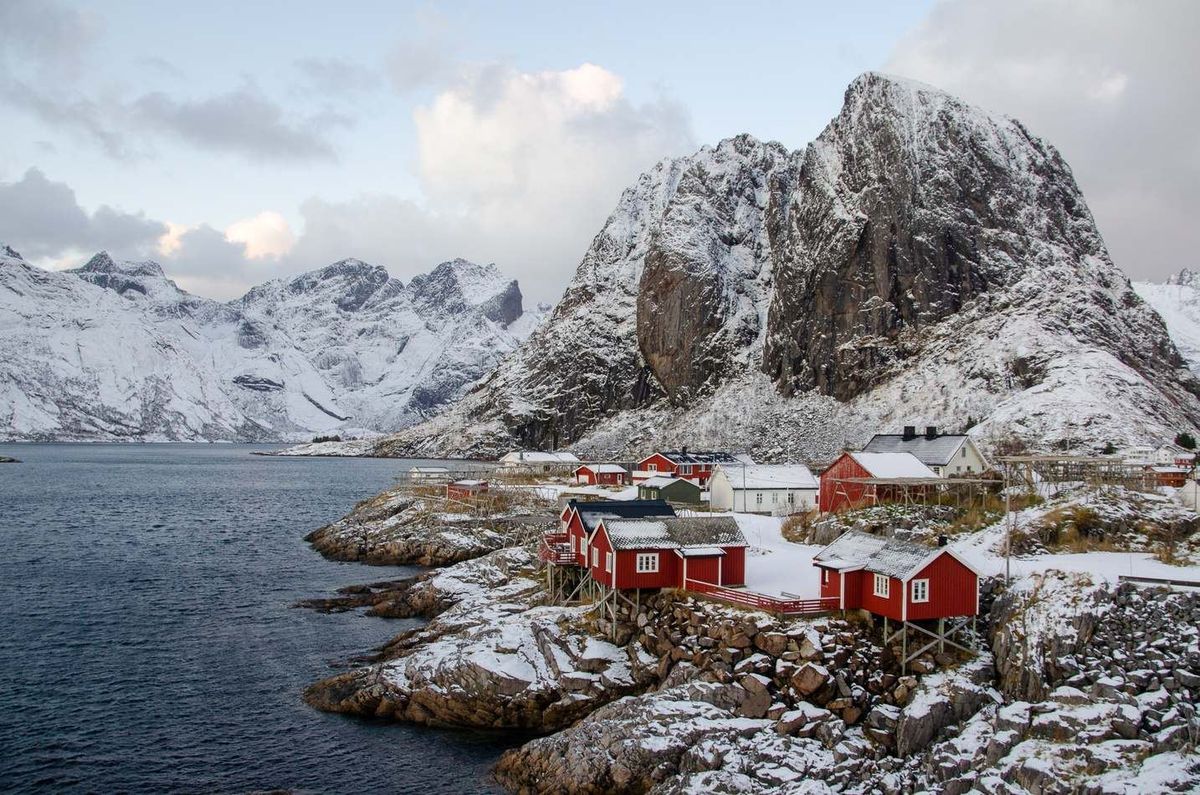 Cabañas rorbu rojas de Hamnøy sobre el agua con montañas detrás