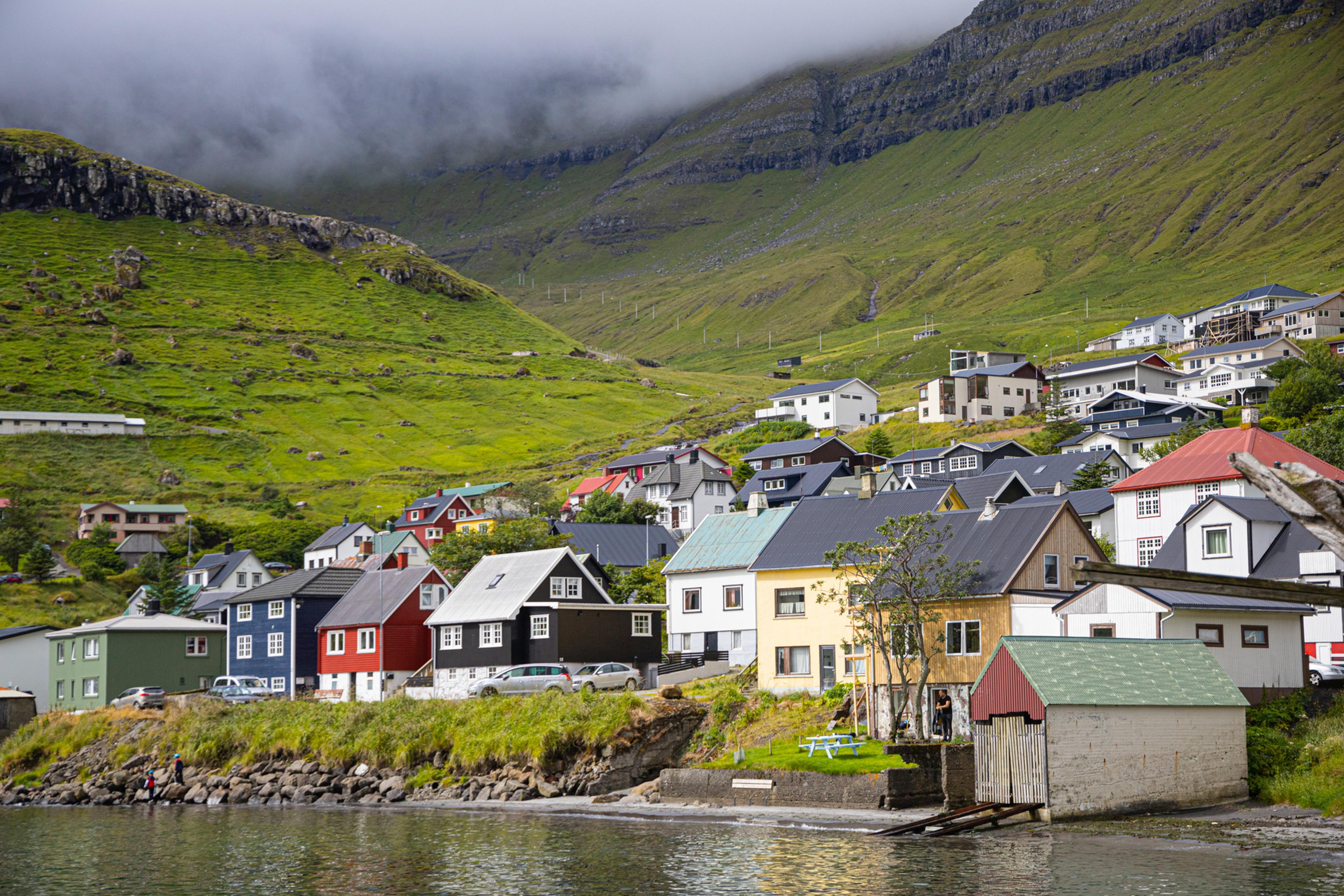Casas de colores al borde del agua bajo laderas verdes en un fiordo de las Islas Feroe