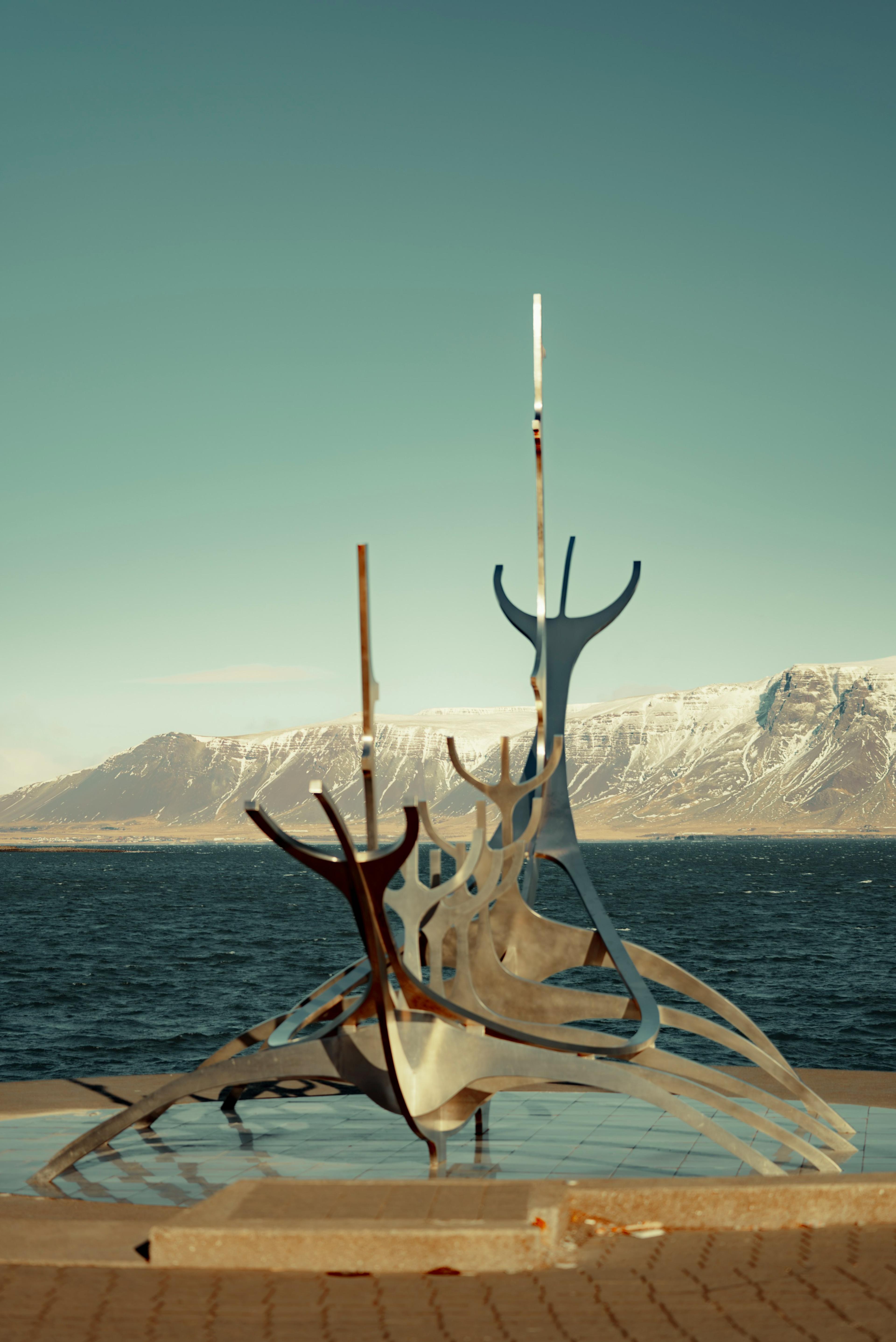 Escultura Sun Voyager junto al mar en Reikiavik, con montañas nevadas al fondo