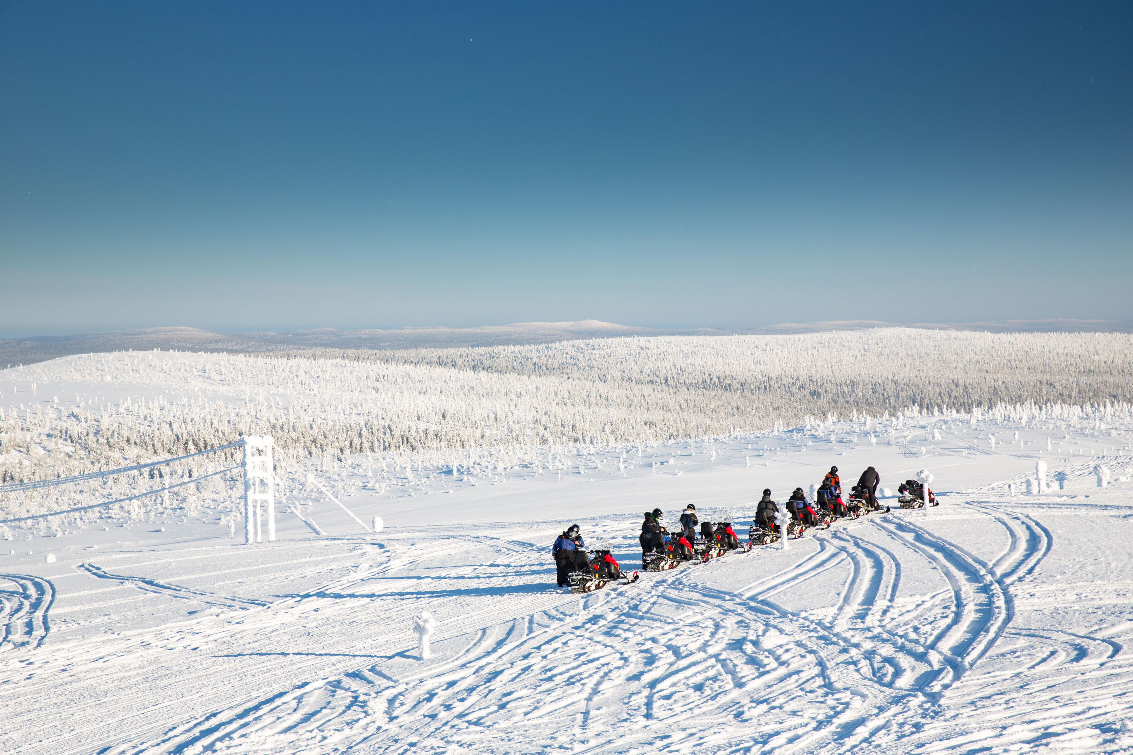 Grupo de motos de nieve en fila sobre una extensión helada en Laponia Sueca