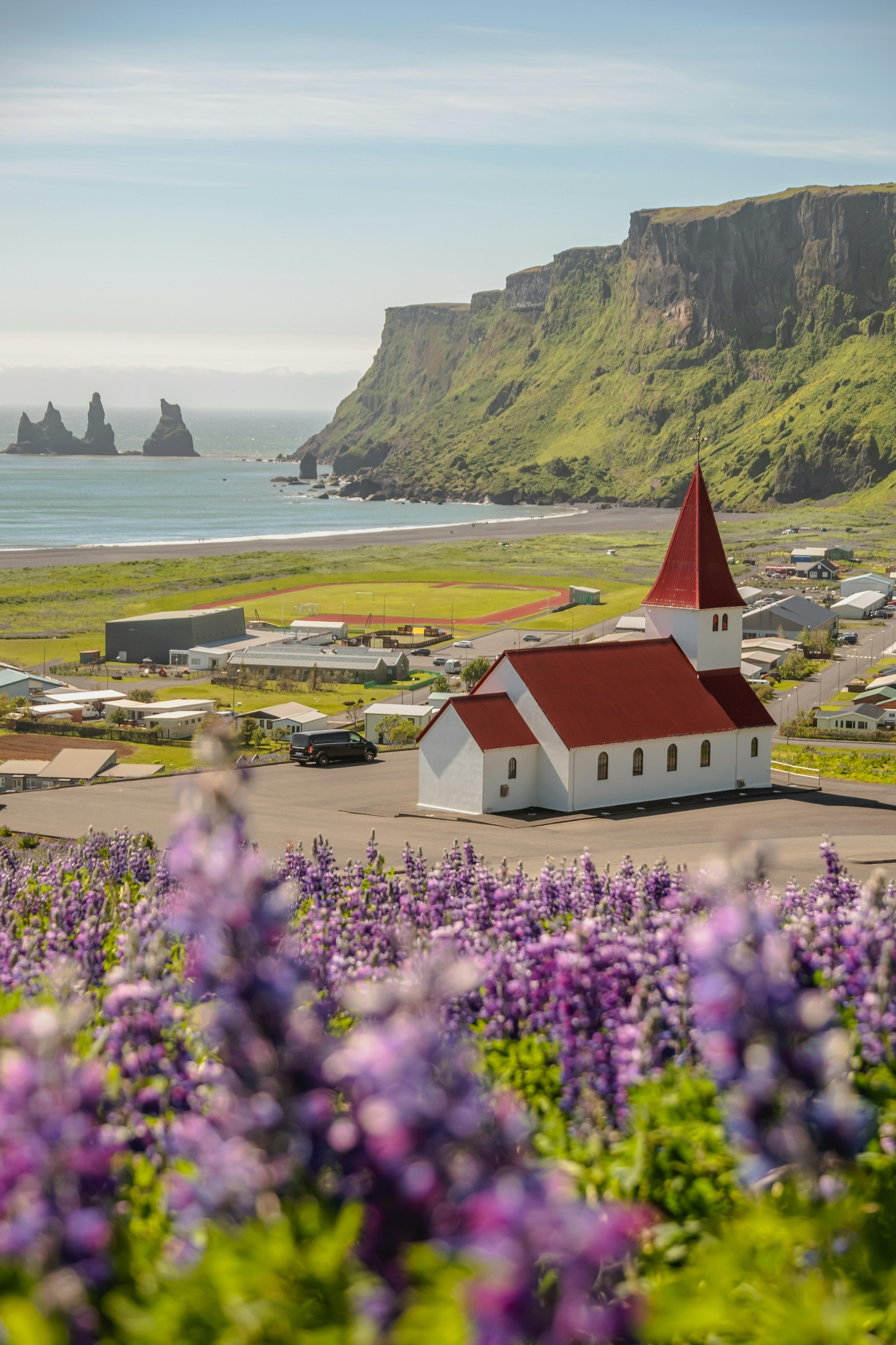 Iglesia de Vík sobre la ladera con el mar y los acantilados al fondo, costa sur de Islandia