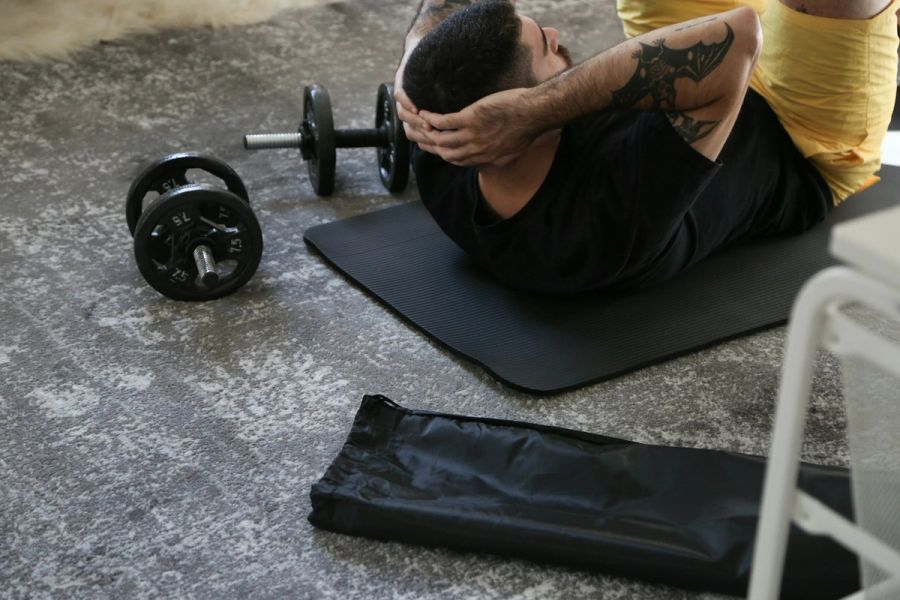 Man doing a programmed workout at home on a mat with a barbell