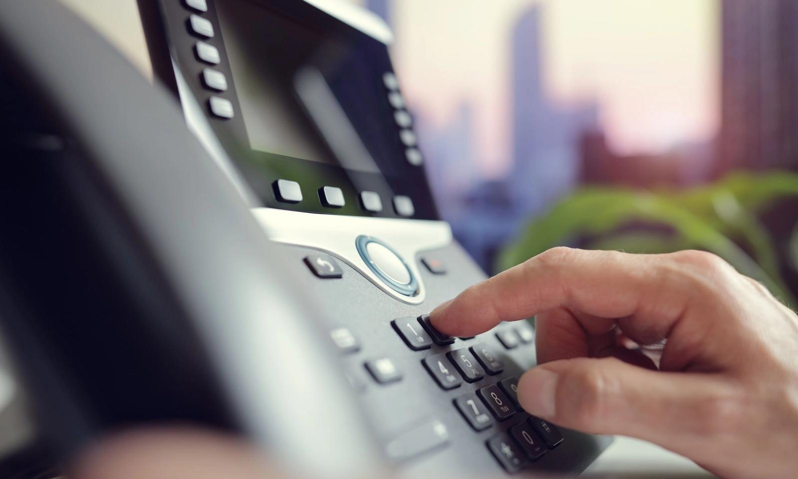 A finger dialling on an office IP desk phone