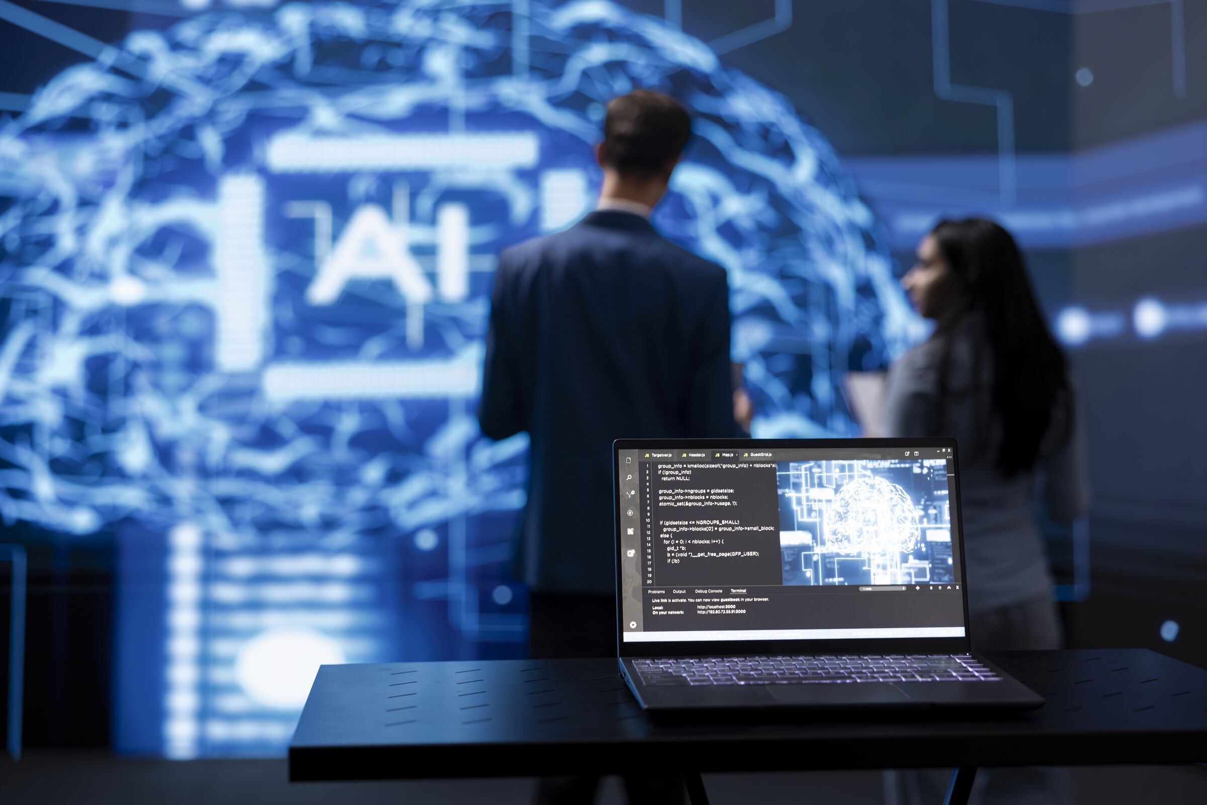 A laptop running AI software in front of a large AI display