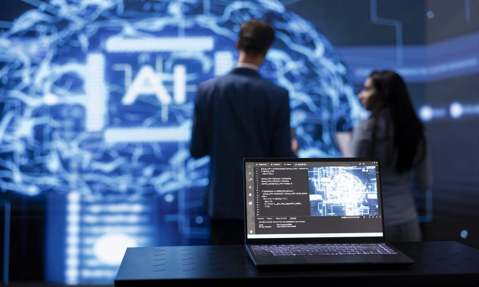 A laptop running AI software in front of a large AI display