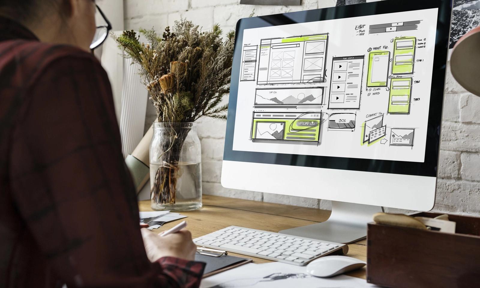 A designer sketching website wireframes on a desktop computer