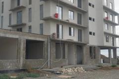 A residential building nearing completion — finished facade, balconies and the frame section of the ground floor