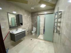 A finished bathroom — marble cladding and a shower cabin