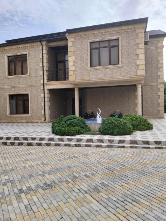 A two-storey private house — stone-clad facade, columned porch and a paved yard