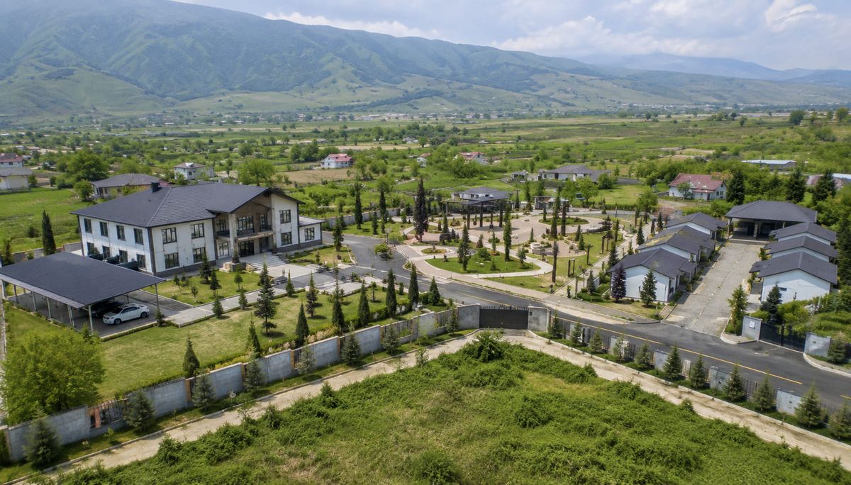 An aerial view of a residential development in Khojaly — private houses, a public building, asphalted roads and a landscaped park area