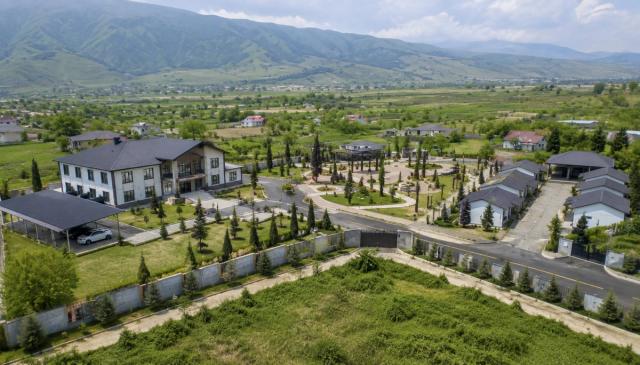An aerial view of a residential development in Khojaly — private houses, a public building, asphalted roads and a landscaped park area