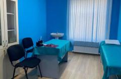Reception room of a medical worker — desk, armchairs, washbasin, examination couch and a window with blinds