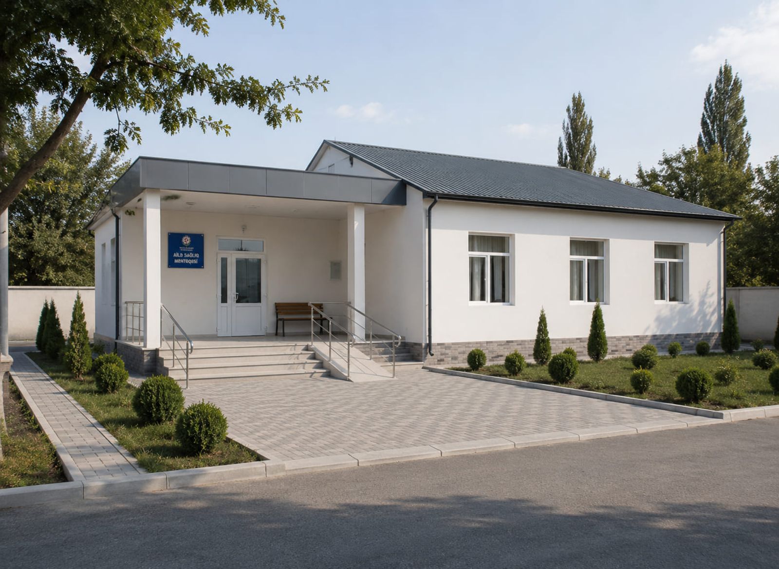 A family health centre building after renovation — a white plastered facade, a dark roof covering, a covered entrance, a ramp and a new pavement