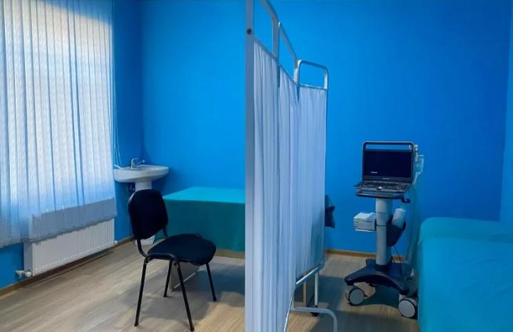 Müayinə otağı — mavi divarlar, pərdə arakəsmə, müayinə çarpayısı, ultrasəs aparatı və yeni radiator