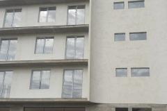 A plastered and clad five-storey building — windows fitted, shopfront frames on the ground floor