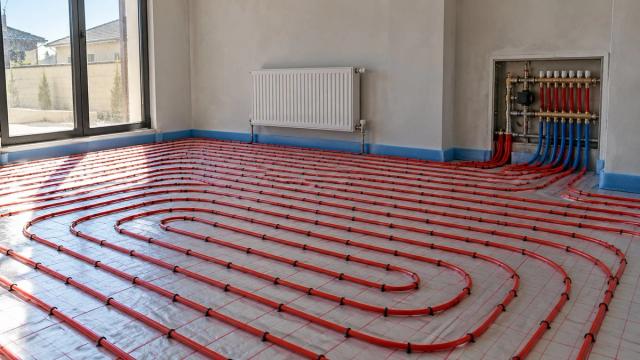Boş otaqda döşənmiş isti döşəmə boruları, radiator və kollektor