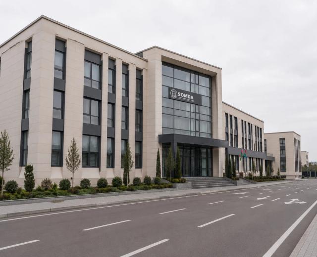 The clad facade of an administrative building — light-coloured cladding panels, dark vertical strips and a glazed entrance group