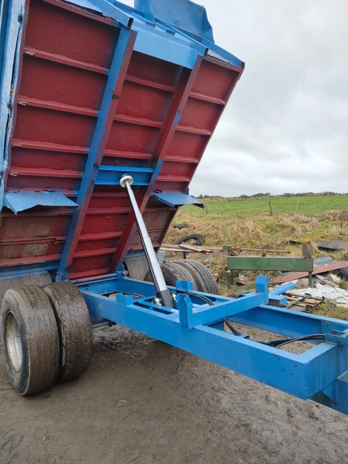 Tipping trailer raised on its new ram and chassis, in a farm yard