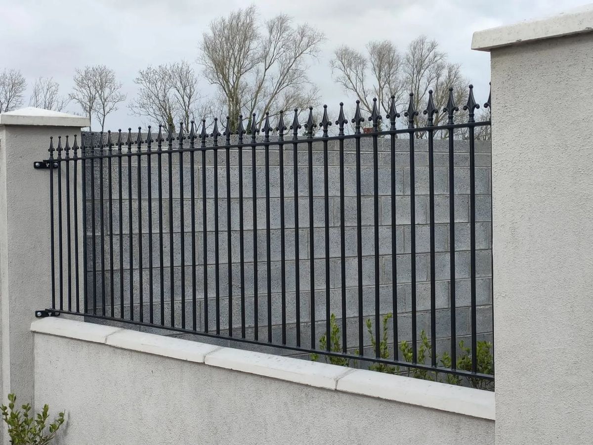 Black spear-top railings fitted between rendered pillars