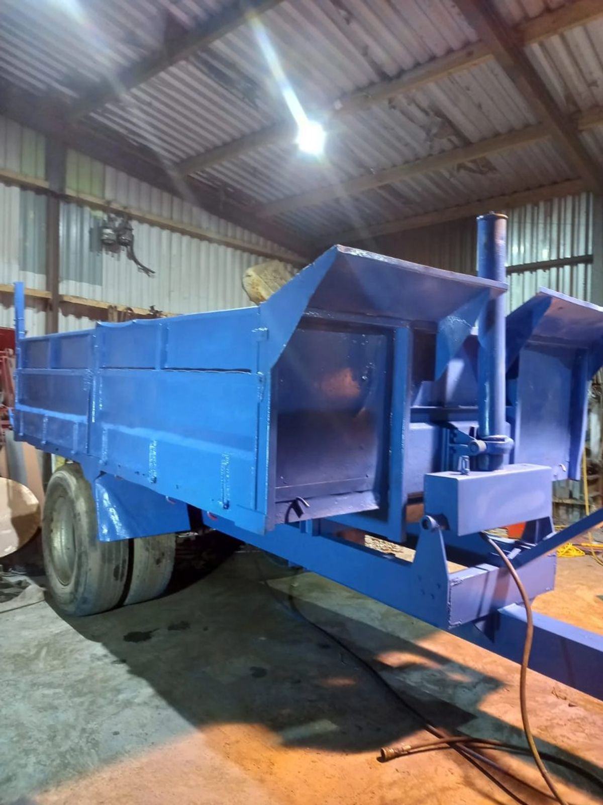 Tipping trailer with its old body refitted on a new chassis, painted blue, in the workshop