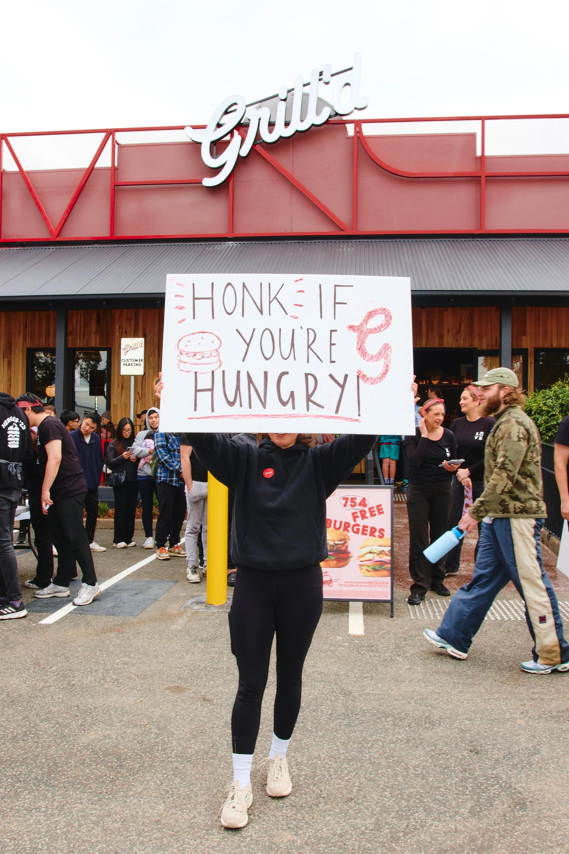 Girl holding a sign that reads honk if you're hungry