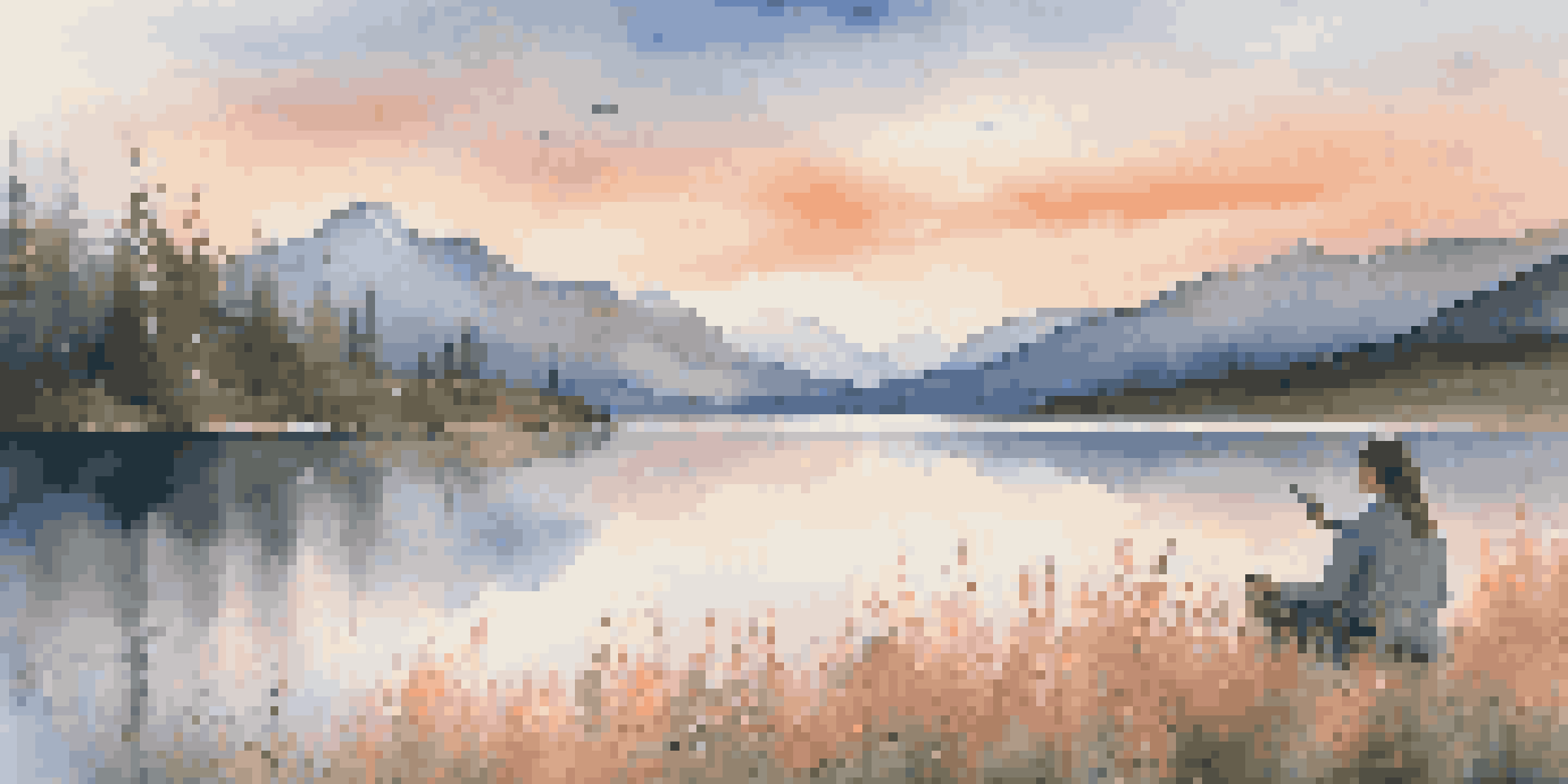A tranquil lake at sunset with mountains in the background and a photographer capturing the view.
